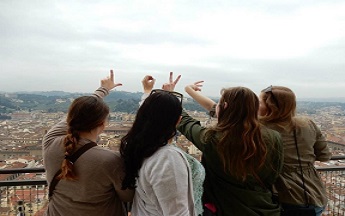Four students looking over a city and holding their hands out to spell out the word "Love"